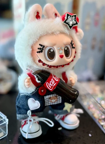 Labubu Nº 03: white hood with a star pin, crystals around the eyes and a cola bottle in hand.