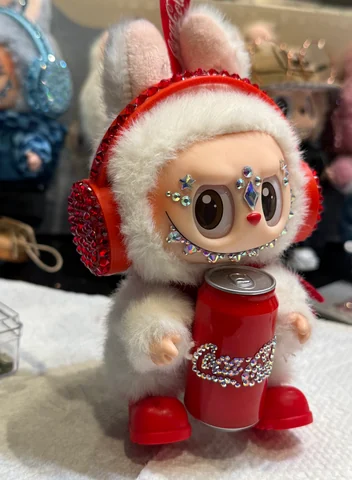 Labubu Nº 04: red crystal ear muffs, white fur, a crystal cola can and red boots.